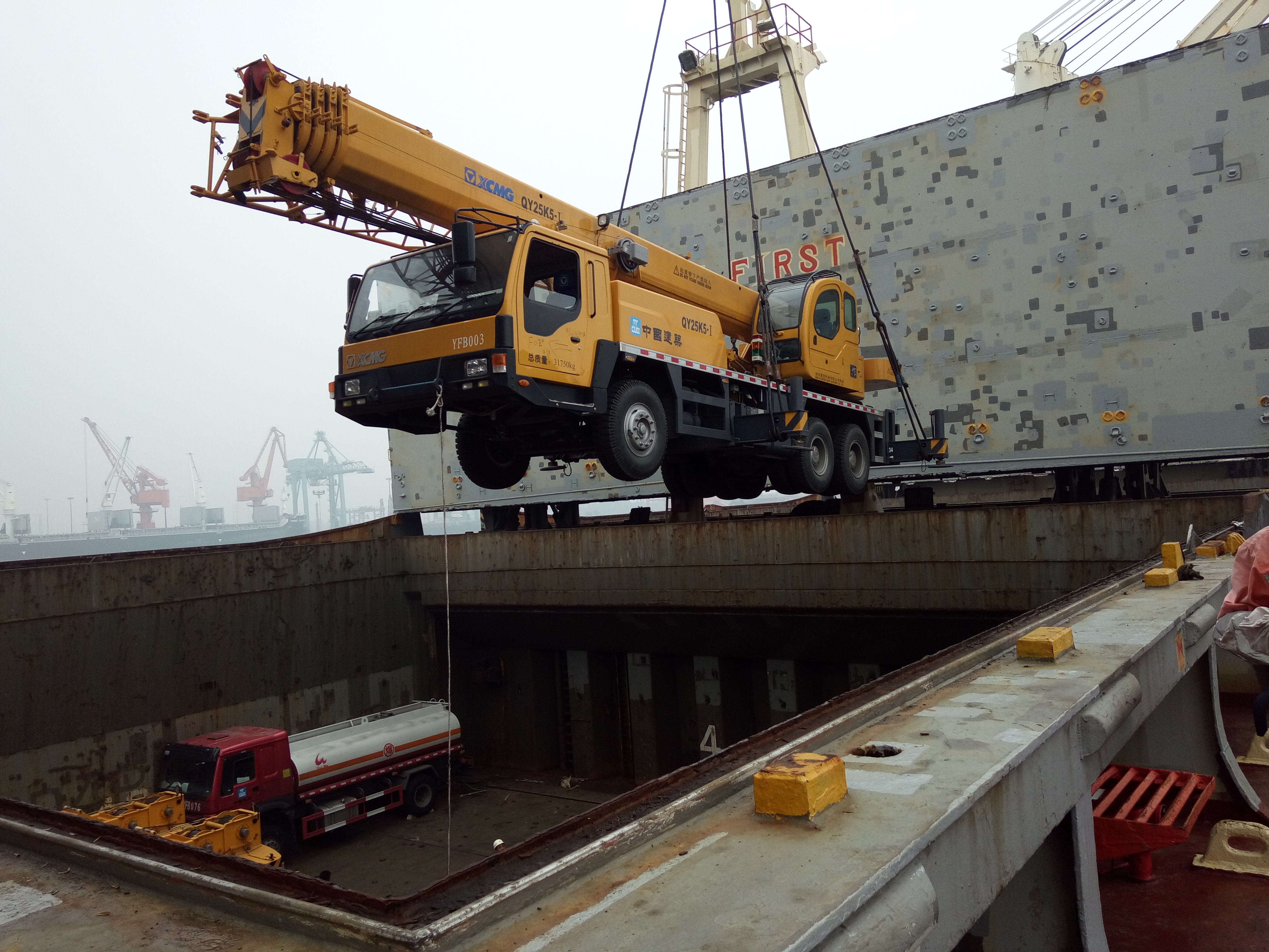 XCMG mobile crane being lifted into a cargo vessel at port